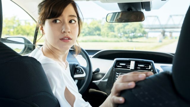 young woman driver turning back.