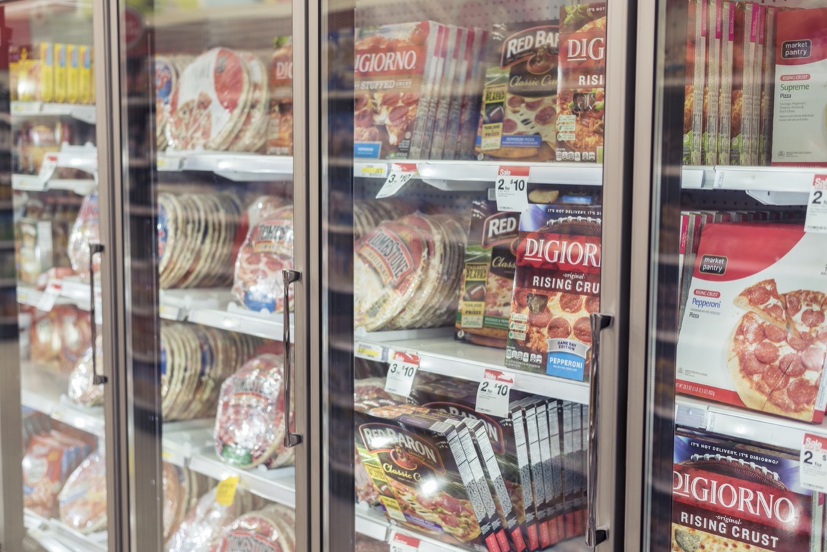 supermarket freezer case full of frozen pizzas