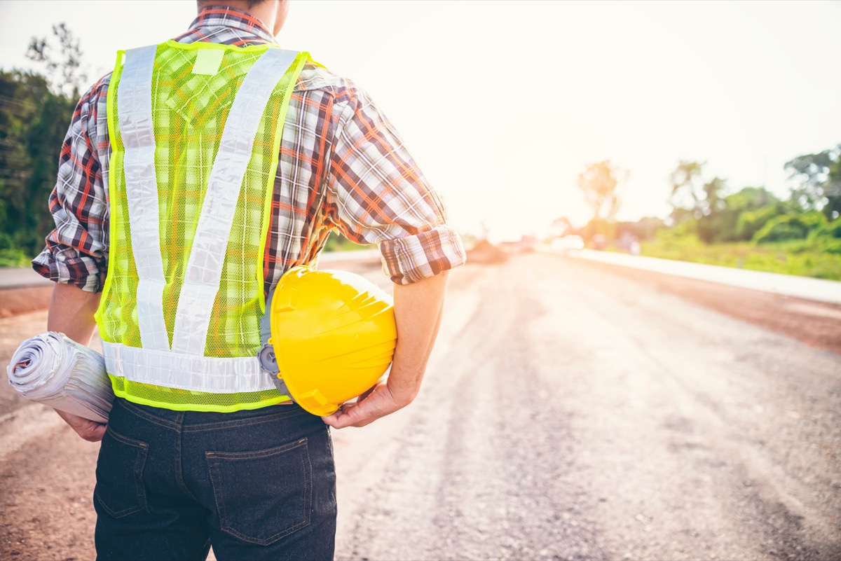 highway maintenance worker in yellow vest holding hard hat