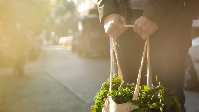Man with face mask and fabric shopping bag.