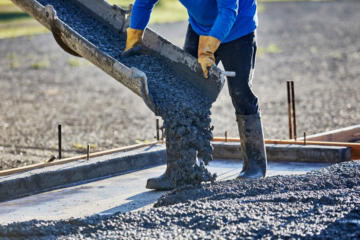 person pouring cement from chute outdoors