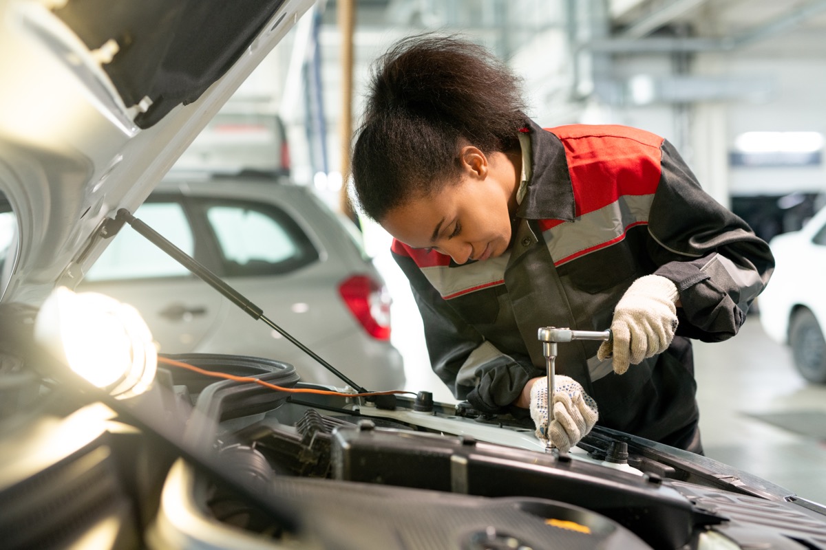 young female mechanic working on car