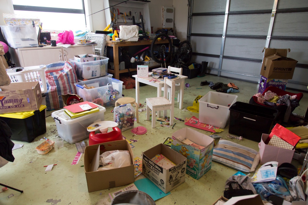 cluttered garage with boxes and mess on the floor