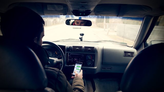 Guy looking at his phone while driving