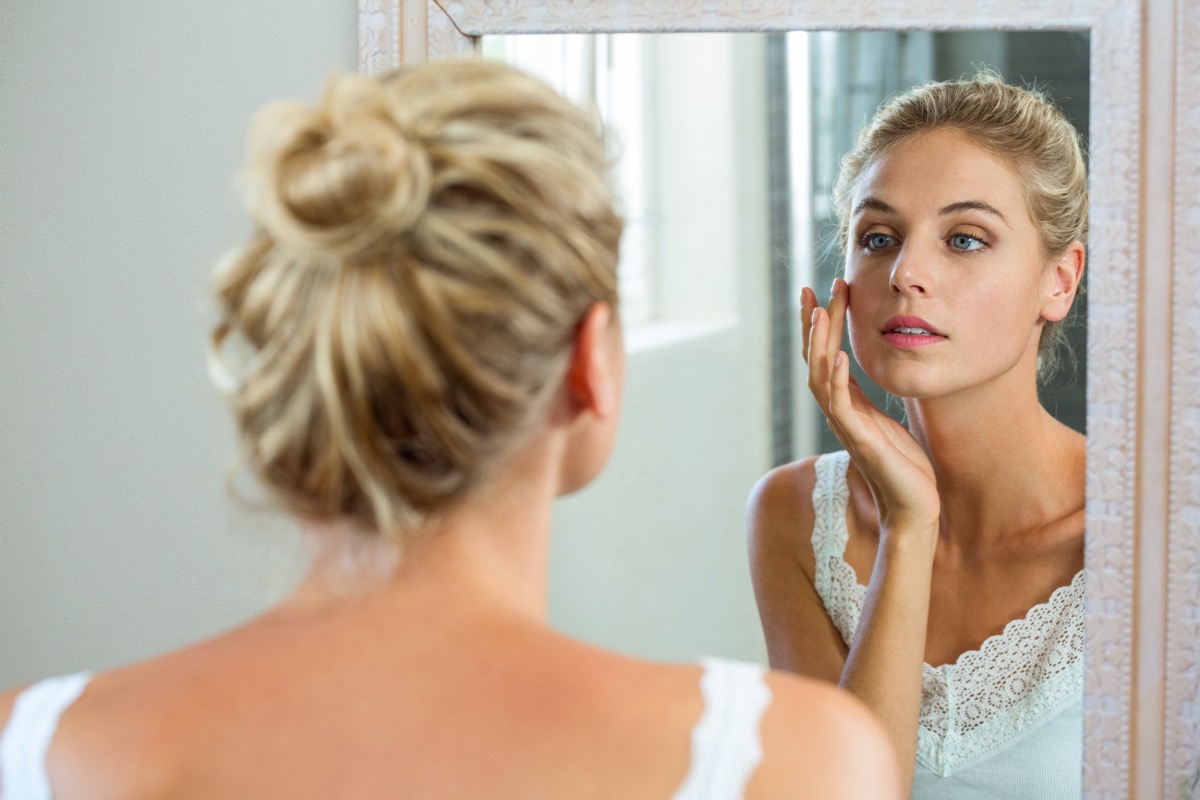 Woman looking at her face in the mirror