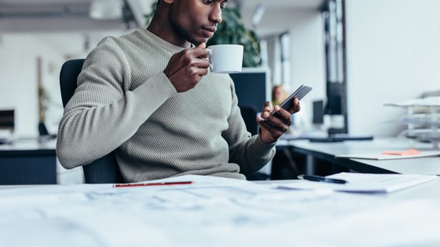 young man at office looking at smartphone