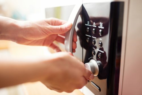 Closeup of hands operating microwave