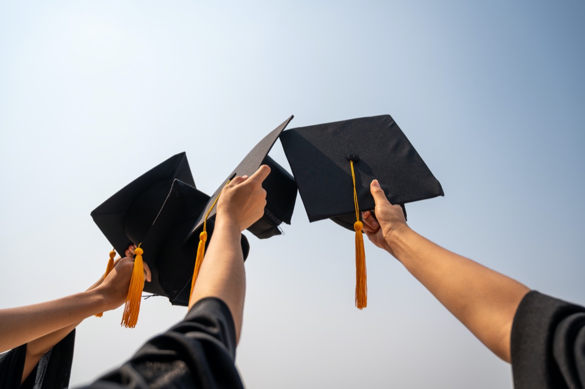 Graduates holding up caps