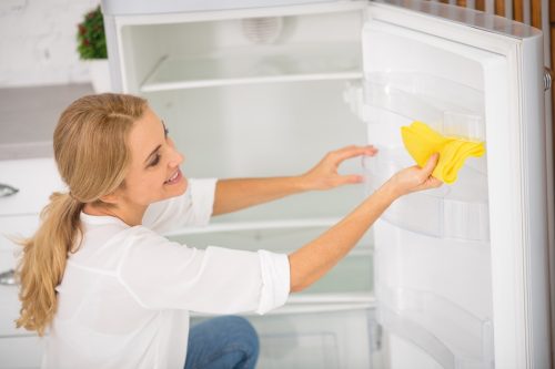 Blonde woman cleaning fridge