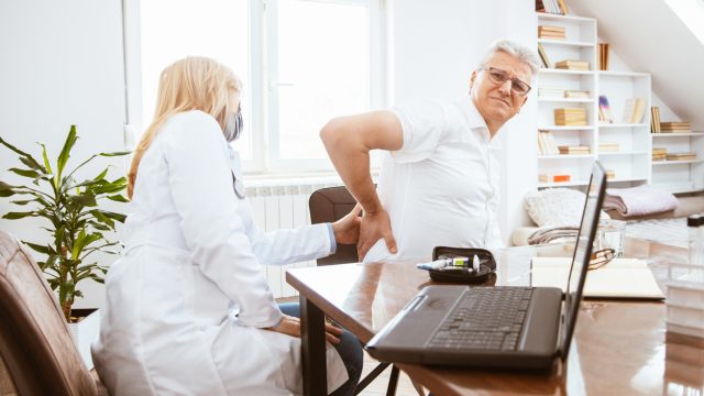 A doctor examining a man's kidneys in her office