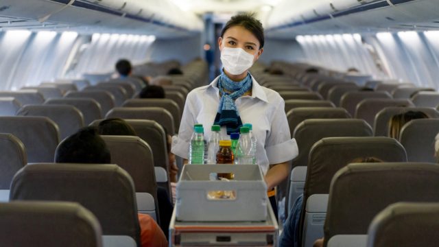 A flight attendant serving drinks on a plane