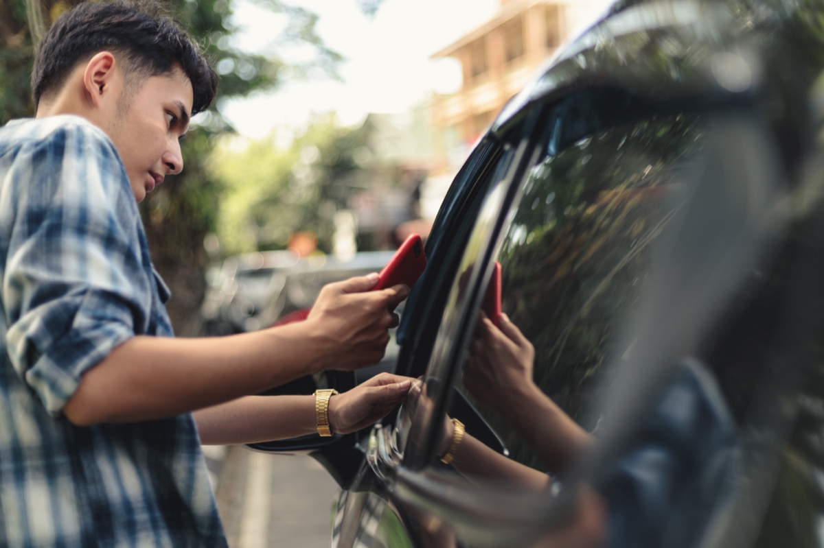 man looking at phone while getting in black cab or taxi or towncar