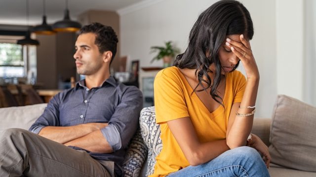 upset 30-something couple arguing on couch