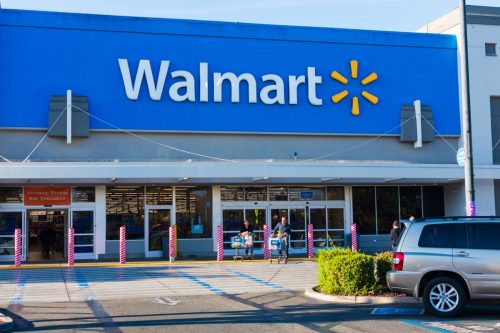 Happy customers leaving Walmart store with full shopping carts.