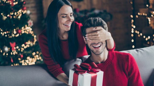 A woman surprising her husband with a holiday gift