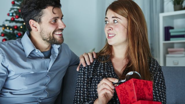 A woman opening a gift she doesn't like from her partner.