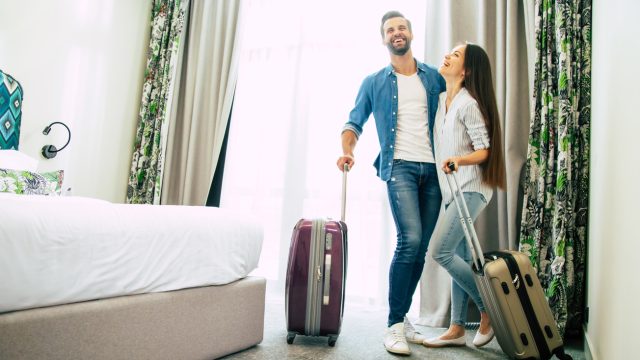 A young couple standing in a hotel room hugging