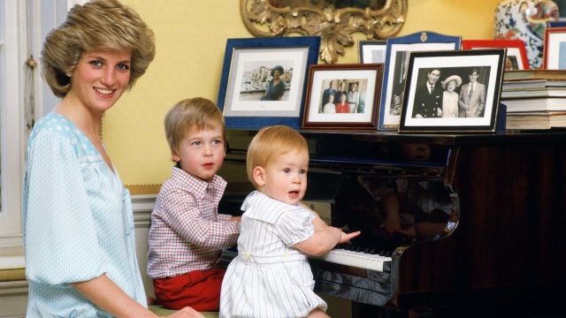 Princess Diana, Prince William, and Prince Harry sitting at a piano in Kensington Palace in 1985