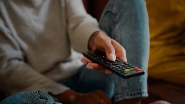 Woman hand holding television remote at home