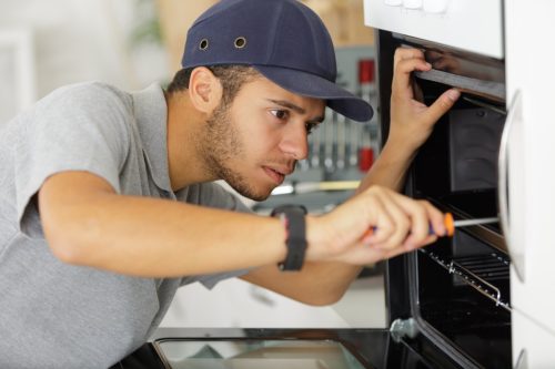 young man in baseball cap repairing stoves