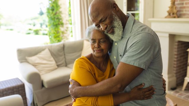 Couple embracing with eyes closed in living room. retreat, retirement and happy senior lifestyle concept.