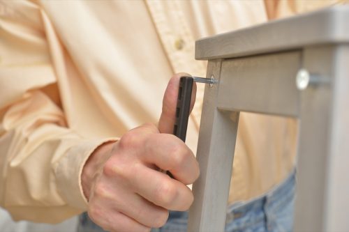 Man assembling the step stool. Selective focus on the Allen key