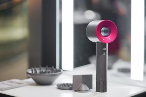 A photo of dyson modern tools applicaces and beauty tool with soft focus on the shocking pink hair dryer. Soft focus and slightly grained filer.