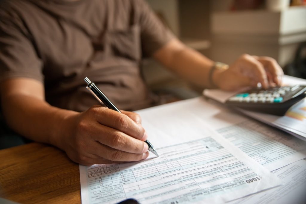 close up on person using calculator and pen to fill out 1040 form