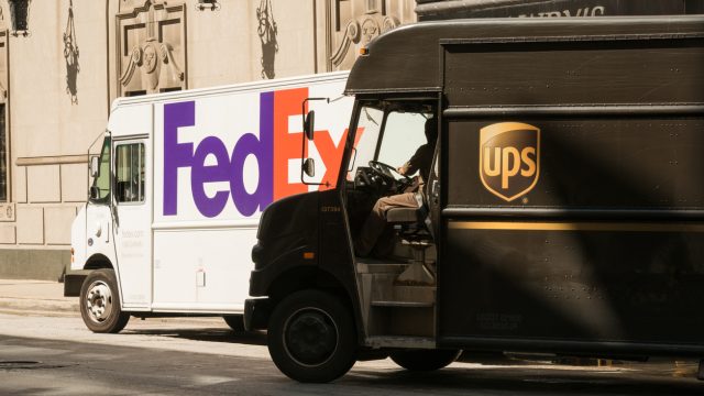 A UPS and FedEx delivery truck next to each other on the street