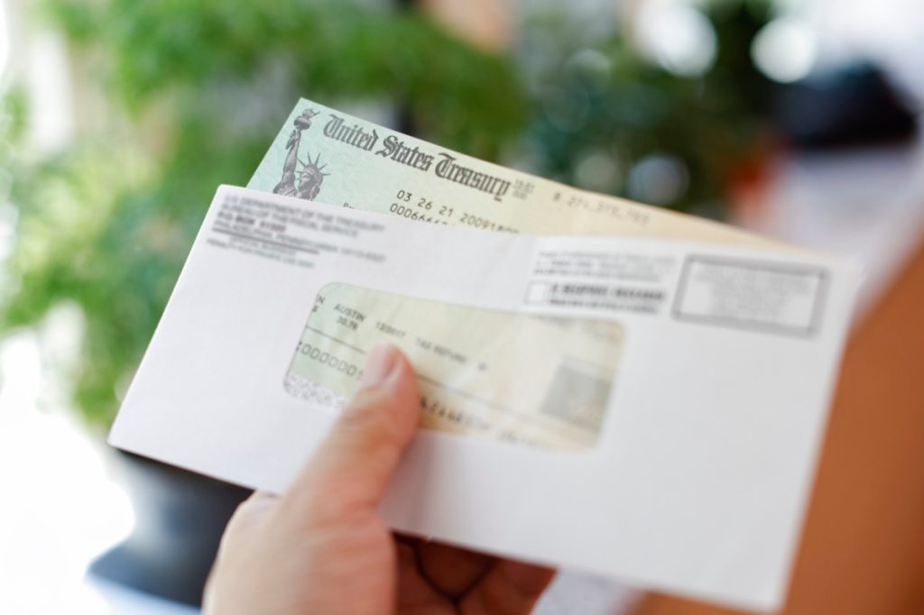 Close-up on hand holding check from United States Treasury in envelope