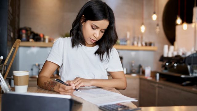 Female cafe owner signing papers calculating business expenses