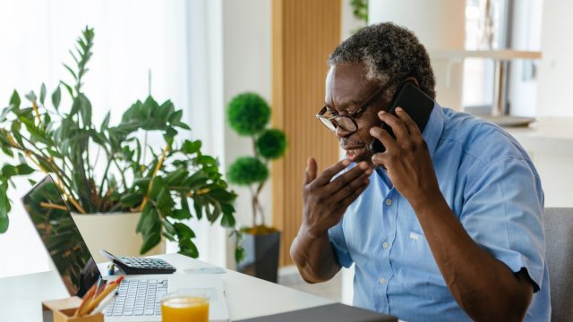 man sitting at the home office and having a phone conversation with the insurance company.