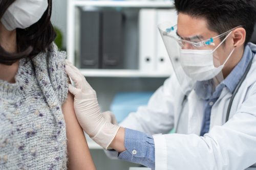 male doctor wear mask, give treatment to young woman in hospital.
