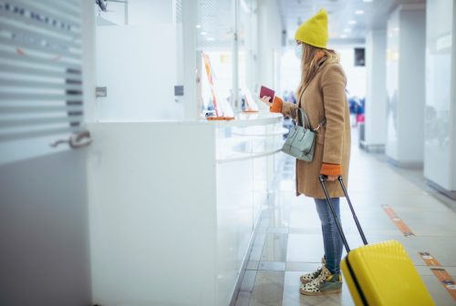 A young woman is at the airport's check out counter. She's waiting to leave the airport as soon as the customs officer checks on her passport.