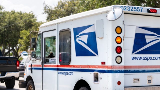 Small USPS van truck delivering packages in Florida, on street road driving