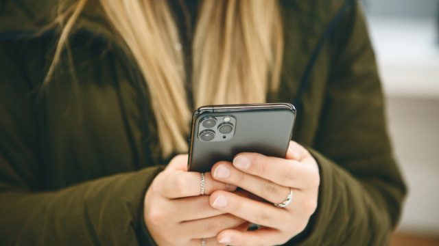 The girl uses a new cell phone with a triple camera.