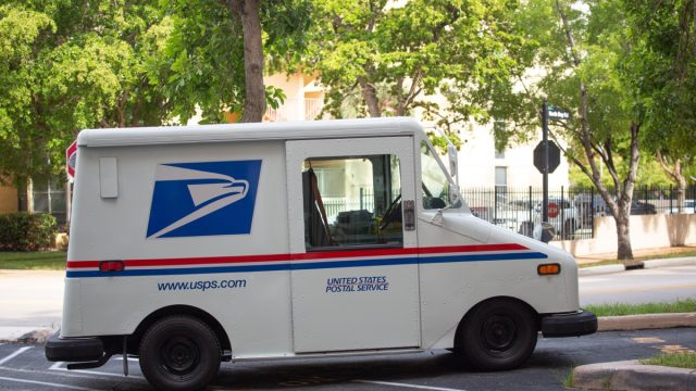 USPS truck parked on street with trees
