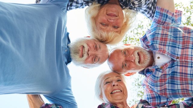 four senior citizens arm in arm