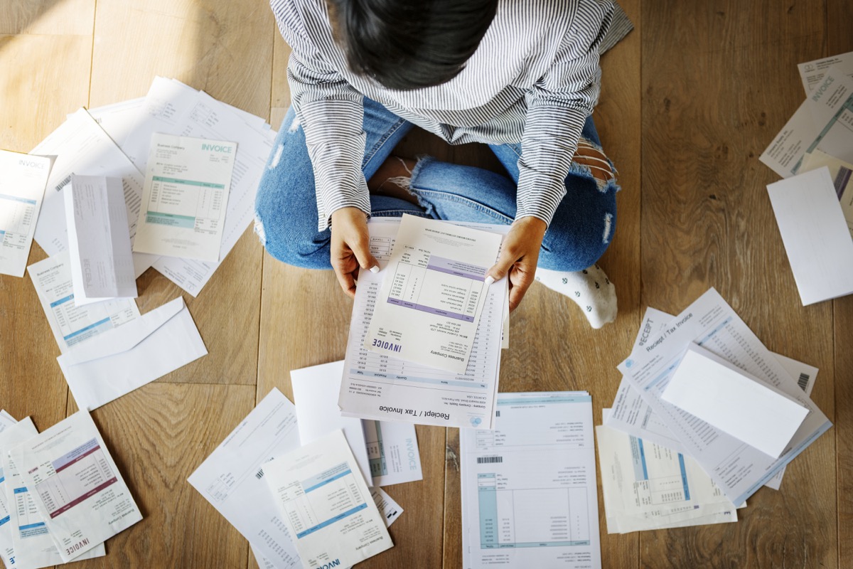 top-down view of a woman sitting on the floor among bills