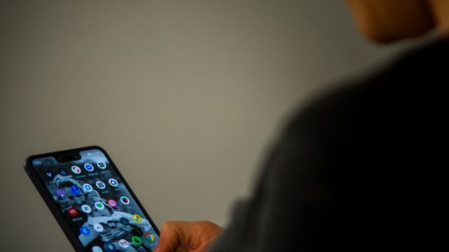 A close up shot of a person using the google pixel phone in a canid scene against a clean background.