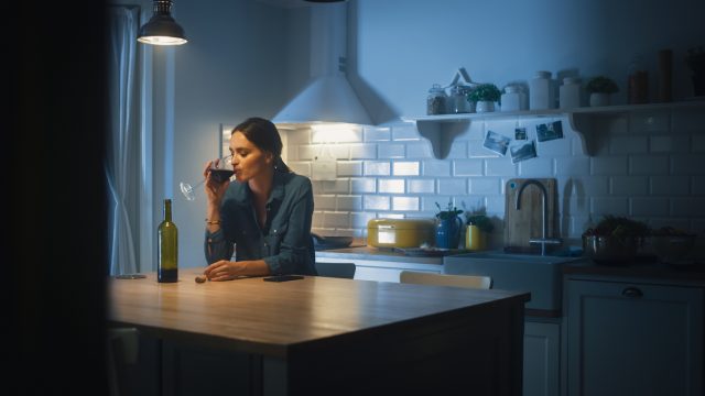 woman drinking wine alone in her kitchen
