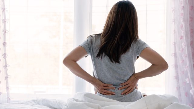 woman waking up in bed with back pain