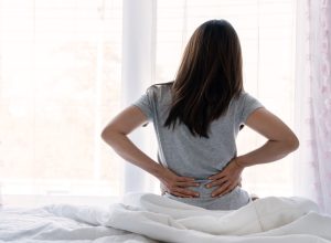woman waking up in bed with back pain