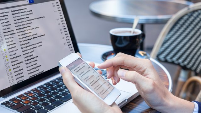 A close up of a person checking their email on a laptop a smartphone