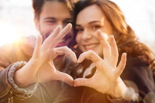 young couple making a heart of their hands