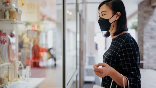 woman wearing protective face mask and looking at the store display of a gift shop