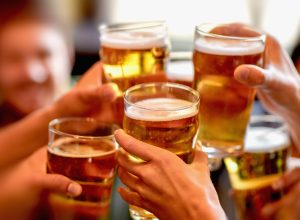 A closeup of a group of friends cheersing with pint glasses full of beer