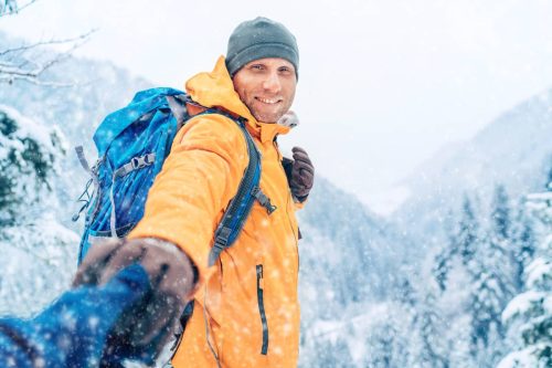 Man hiking in snow leading a woman by the hand