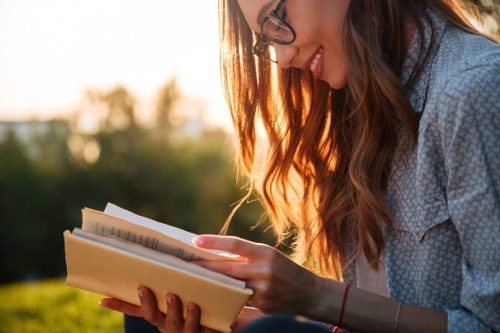 woman finding different "i love you quotes" from a book in the park