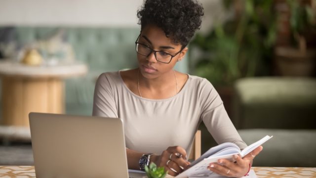 Focused Young Woman with Laptop and Notebook